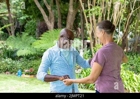 Happy multiracial senior couple dancing together in backyard Stock Photo