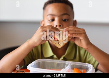 Close-up of african american elementary schoolboy eating sandwich during lunch break in class Stock Photo