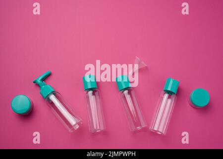 Various transparent empty plastic bottles and jars for cosmetics on a pink background, top view Stock Photo