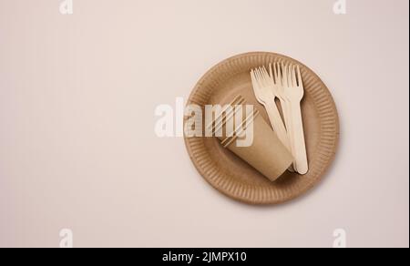 Brown paper cups and plates on a beige background. Recyclable garbage, rejection of plastic Stock Photo