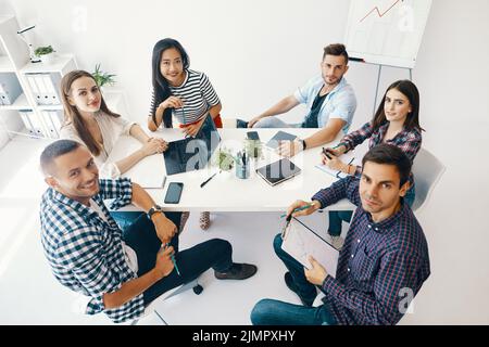 Smiling diverse group of young people working and communicating together in office Stock Photo