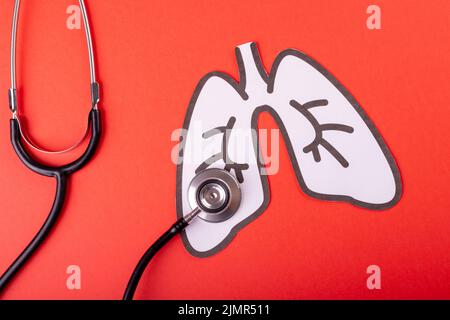 Overhead view of stethoscope with white paper lungs against red background, copy space Stock Photo