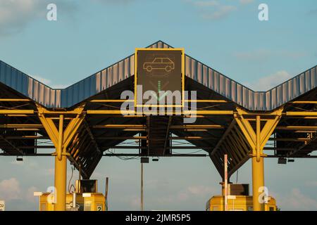 Expressway checkpoint on tollgate roadway on sunny day. Sign allows driving car through tollgate against clear blue sky close low angle shot Stock Photo