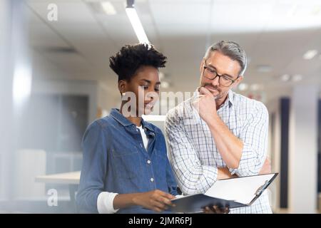 Confident biracial colleagues planning together while discussing over file at modern workplace Stock Photo