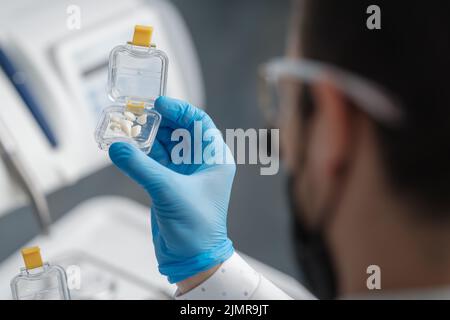 Transparent transportation box with veneers made of pressed ceramics in hands of orthodontist in a dental office Stock Photo