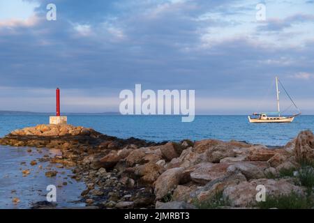 Lighthouse and Sailboat bathed in afternoon light in Potamos Liopetri fishing village, Mediterranean, Cyprus Stock Photo