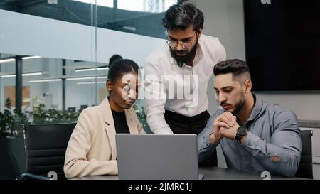 Arab man coach leader boss talking about mistake explain Indian teacher mentor teaching interns managers employees use online app help with software d Stock Photo