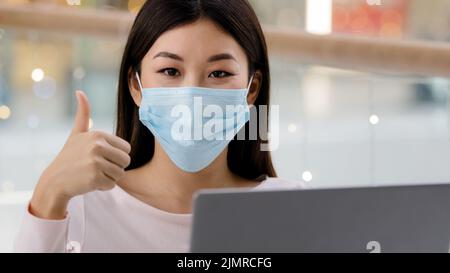 Asian korean successful satisfied business woman worker freelancer student girl designer specialist in face medical mask with laptop looking at camera Stock Photo