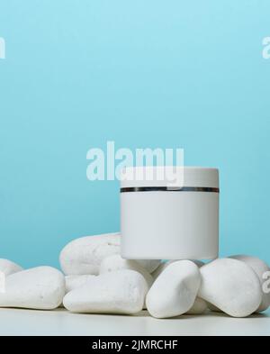 White round plastic jar for cosmetic products on a blue background. Stock Photo