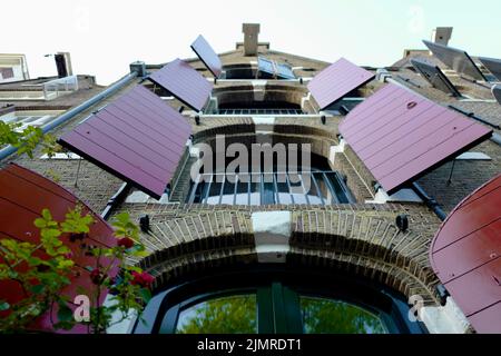 Merchant house with red open window shutters in Amsterdam Stock Photo