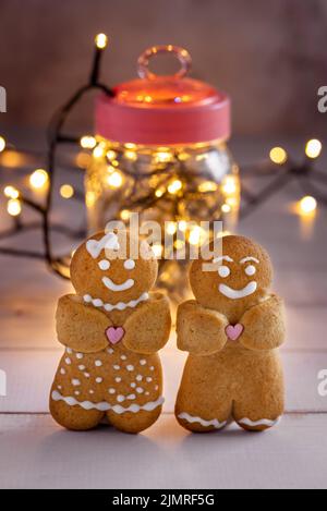 Two gingerbread men on the background of a jar with garlands. Stock Photo