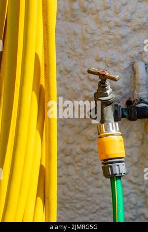 A hosepipe attached to an outside tap Stock Photo