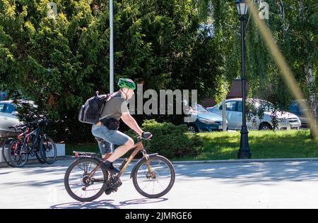 Man riding a bicycle along the pedestrian part of the street. Ukraine, Zhitomir, July 21, 2022 Stock Photo