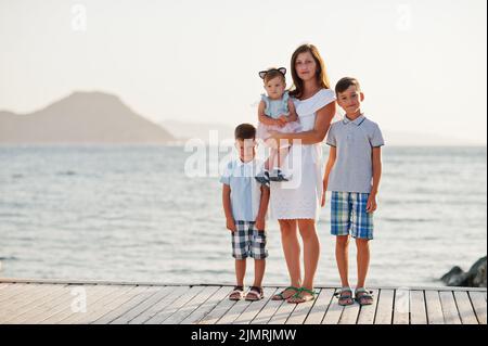 Mother with three kids at Turkey resort against Mediterranean sea stand on the pier. Stock Photo