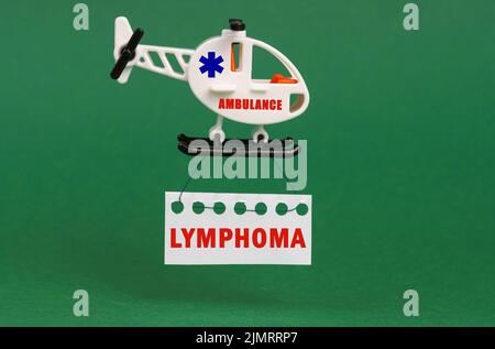 Medical concept. On a green surface, an ambulance helicopter with a sign - LYMPHOMA Stock Photo