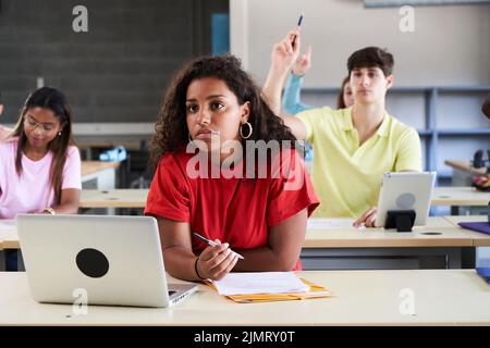 In the Classroom Multi Ethnic Students Listening to a Lecturer. Smart Young People Study at the College. latin girl study with laptop technology Stock Photo