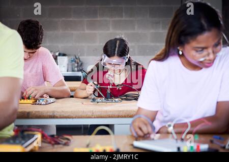 A group of technical college students are in the classroom studying, practicing soldering pieces of hardware on a circuit board. Concept of higher Stock Photo