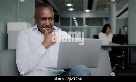 African senior businessman assistant talks in video chat conference consults business clients remotely uses corporate wifi connection wireless Stock Photo