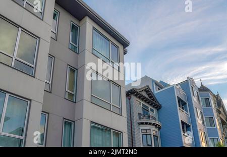 Multi-storey townhomes in the neighborhood of San Francisco, California. There is a modern gray townhouse with picture windows on the left beside the Stock Photo