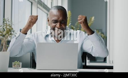African excited happy businessman american executive agent programmer investor win online lottery commercial bet profit celebrate career growth Stock Photo