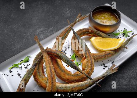 Fried Sargan fish on a plate with sauce and lemon Stock Photo