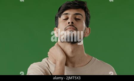 Portrait of exhausted young indian arab man tired overworked man guy feeling physical discomfort massaging male body part tensed muscles having Stock Photo