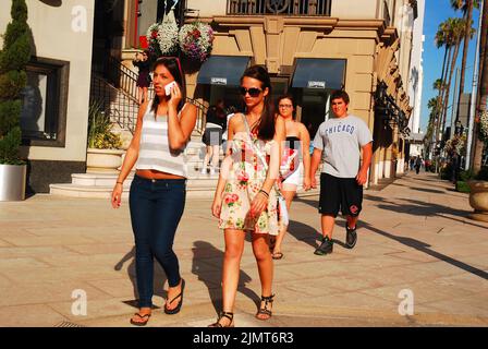 Young people stroll down Rodeo Drive in Beverly Hills, near Los Angeles, shopping and the high end luxury shops  and fashion stores Stock Photo