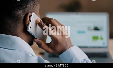 Backside unknown african american man young businessman web designer look at laptop screen surf internet website scroll page interface in social Stock Photo