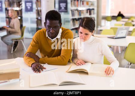 People reading and making notes while preparing for exam in library Stock Photo