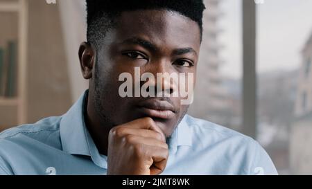 Thoughtful dreamy african man doubtful guy brunet worker businessman hold hand on chin deep in thoughts look distance think about future turns head at Stock Photo