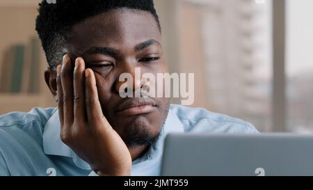 Bored disappointed african man american male businessman have sleeping problem lazy young exhausted guy slumber rest at home workplace feel passive Stock Photo