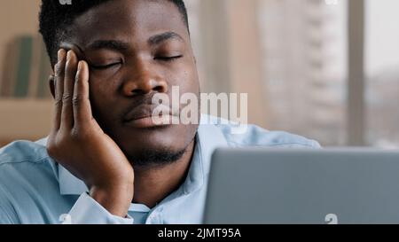 Sleepy tired african man office male dreamer businessman has sleeping problem napping rest at desk american lazy student overworked guy in retire Stock Photo