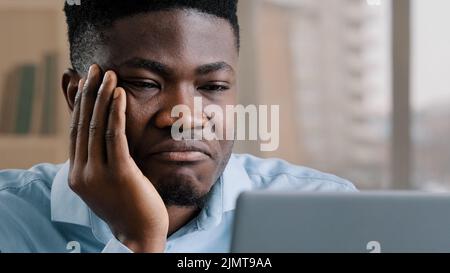 Bored disappointed african man american male businessman have sleeping problem lazy young exhausted guy slumber rest at home workplace feel passive Stock Photo