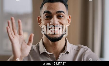 Hispanic handsome business man millennial wave hand greet look at camera arab friendly guy record lifestyle blog provide distance tutorial educational Stock Photo