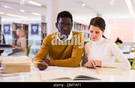 People reading and making notes while preparing for exam in library Stock Photo