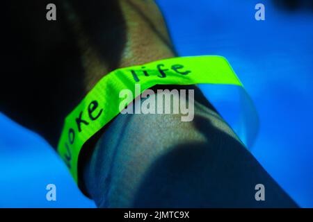 Abstract cover - Close-up of a persons wearing wristband with writing on it with sunlight and shadow reflection . Stock Photo