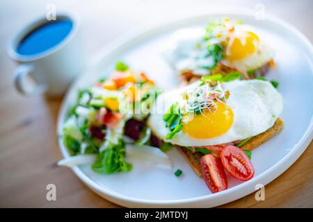 Breakfast with fried eggs on toasts on a restaurant table Stock Photo