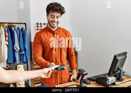 Customer hand paying to shopkeeper man using credit card at clothing store. Stock Photo