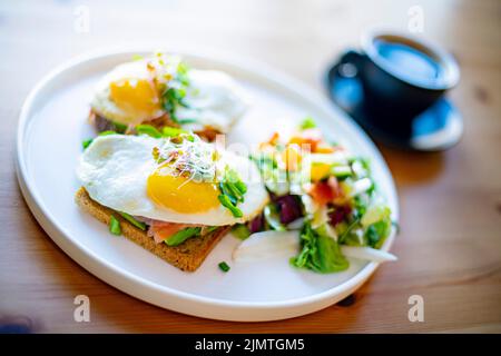Breakfast with fried eggs on toasts on a restaurant table Stock Photo