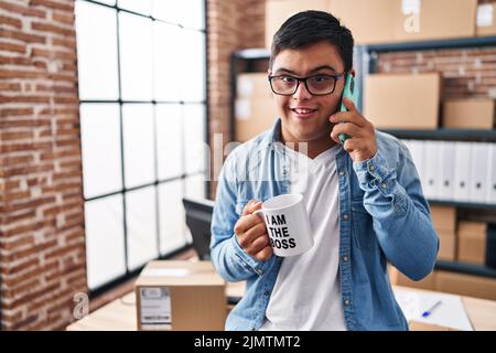 Down syndrome man ecommerce business worker talking on the smartphone drinking coffee at office Stock Photo