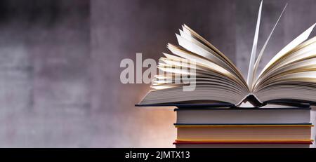 A composition with an open book lying on a stack of other books Stock Photo