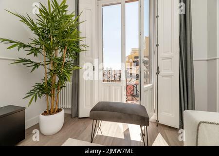 Relaxation area in an apartment next to a balcony with wooden and glass doors through which a large amount of light enters Stock Photo