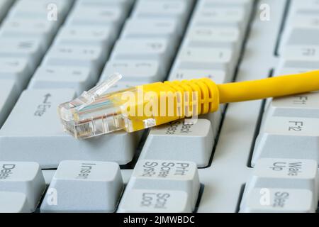 Internet cable, RJ45 plug on computer keyboard Stock Photo