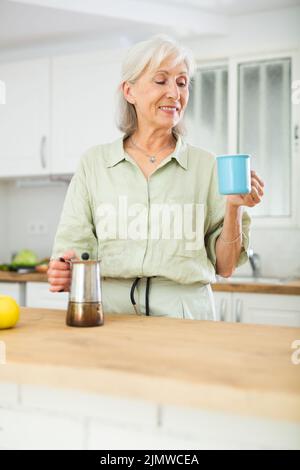 Cheerful senior woman having breakfast with cup of coffee Stock Photo