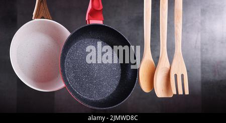 Two hanging frying pans and kitchen utensils Stock Photo