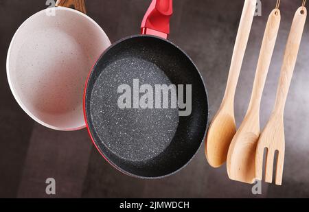 Two hanging frying pans and kitchen utensils Stock Photo