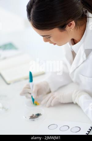 Now I will easily be able to identify my samples. a young scientist using a pen to mark a petri dish in a lab. Stock Photo