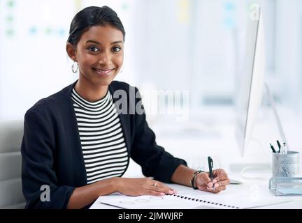 Work hard till things start working in your favor. Portrait of an attractive young businesswoman going over paperwork inside her office at work. Stock Photo