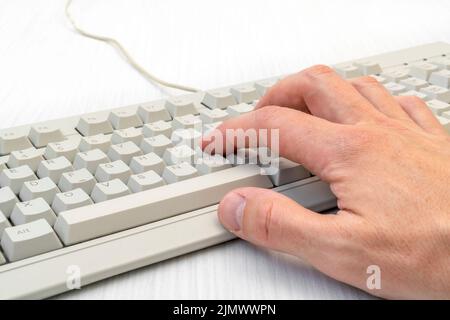 Single hand typing on white keyboard Stock Photo