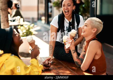 Its always a good time to get ice cream. three friends enjoying ice cream cones while out in the city. Stock Photo